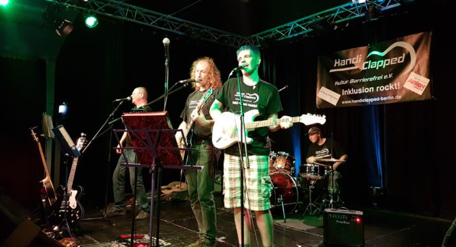 Bild vom dreißigsten Handiclapped Bandworkshop, mit dem Leiter Martin Talin und drei Bandmitgliedern, alle zusammen live auf der Bühne bei der Präsentation auf einem Handiclapped Konzert