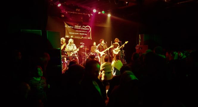 Die fünf Mitglieder der Band Woodman Jam live auf der Bühne, bei einem Konzert von Handiclapped