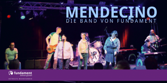 Die Band Mendecino live auf der Bühne, mit dem Schriftzug "Mendecino, die Band von Fundament Wohnen